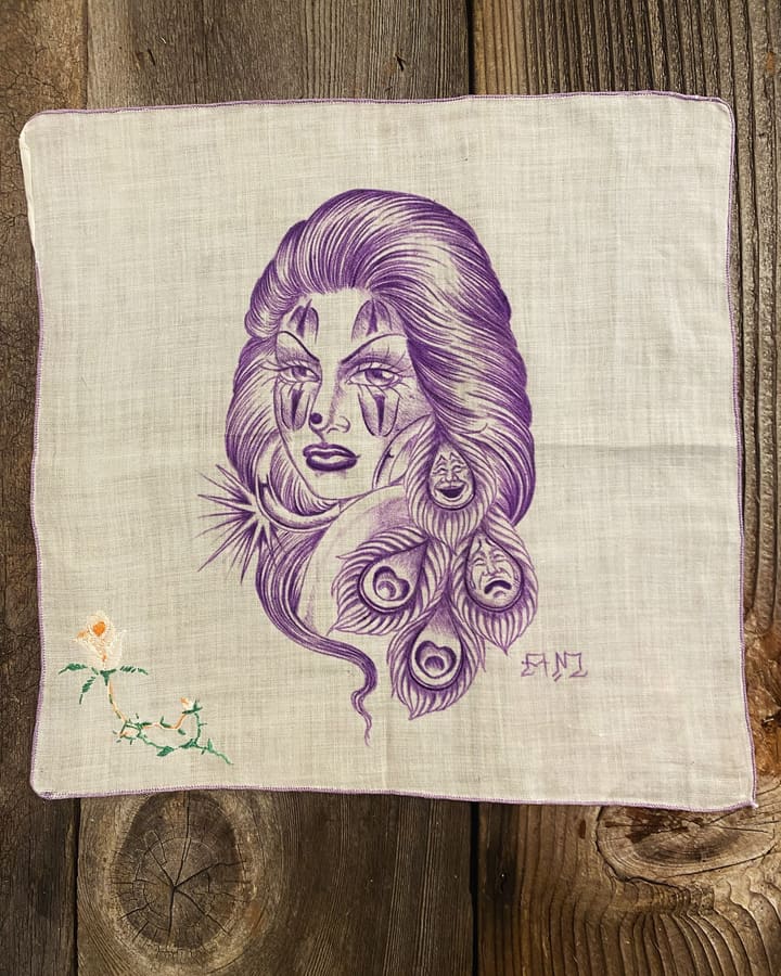 Hand-drawn pañuelos in black ink laid out on weathered wood.