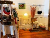 A small vintage corner in 2021: a ladder rack of clothes, a horse painting and a paper lamp.