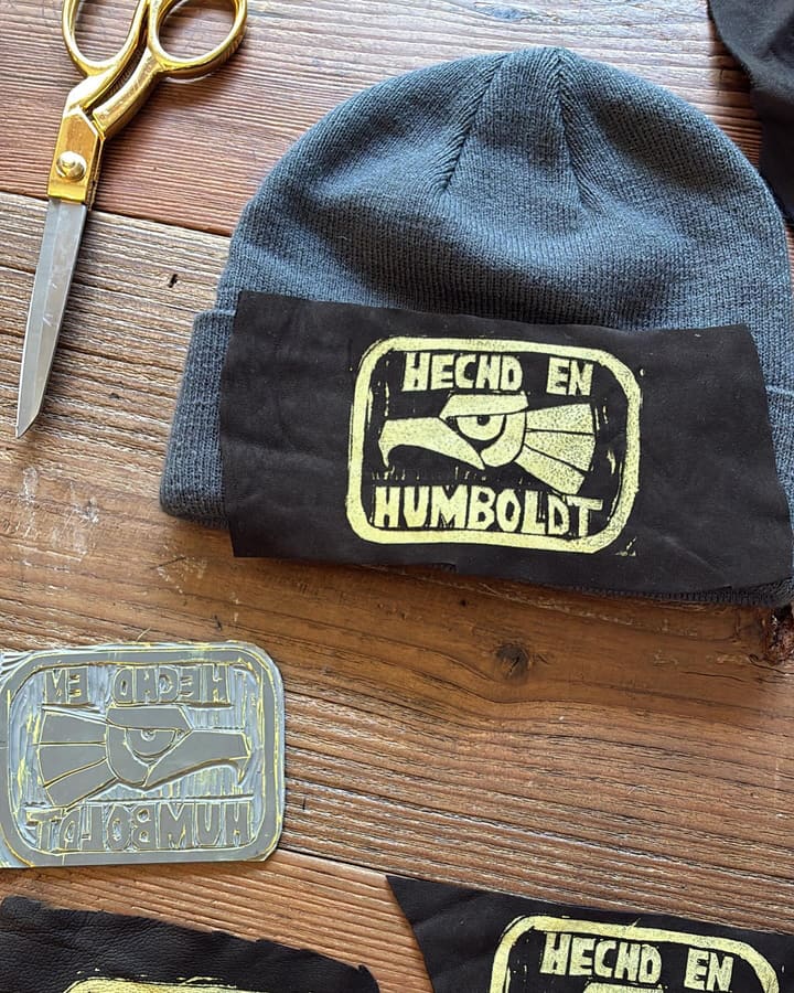 A leather patch stamped “Hecho en Humboldt” next to the carved printing block that made it.