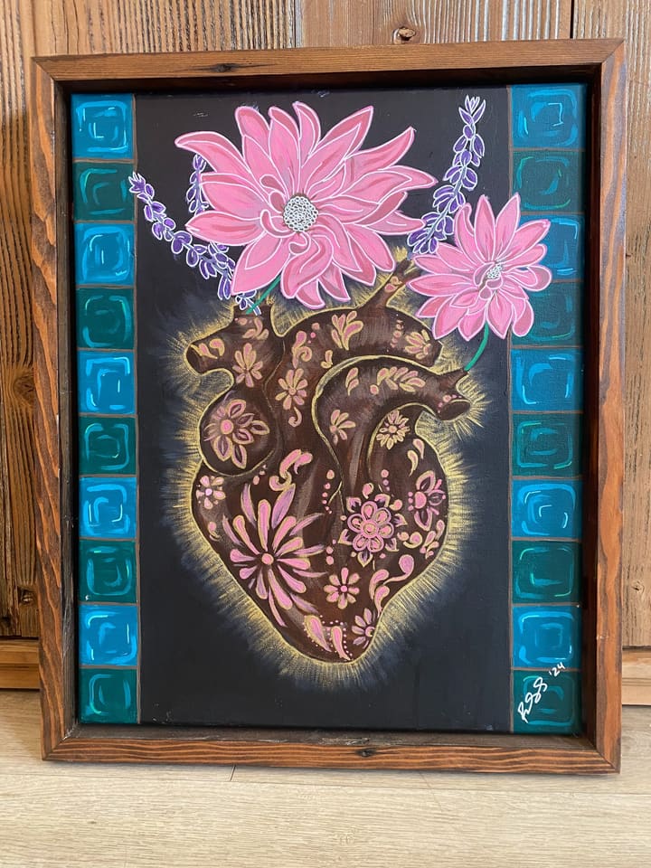 A framed painting of a red sacred heart covered in golden flowers.