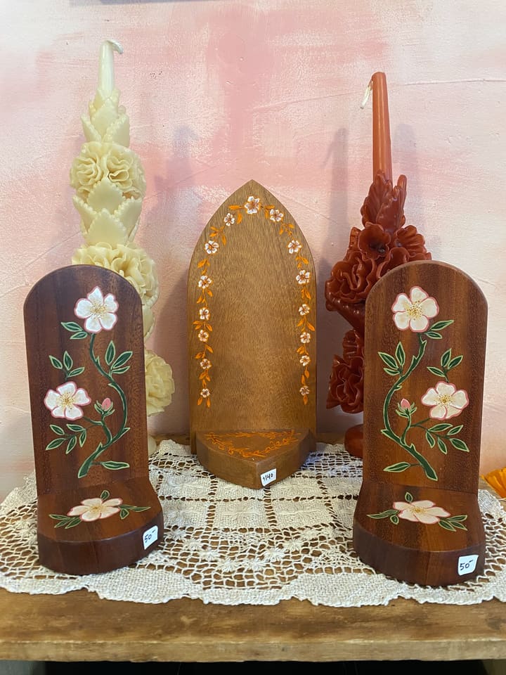 Small hand-painted wooden altars set between carved flower candles.