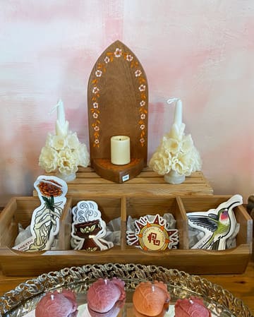 A wooden nicho with candles, carved flower candles and small treasures.
